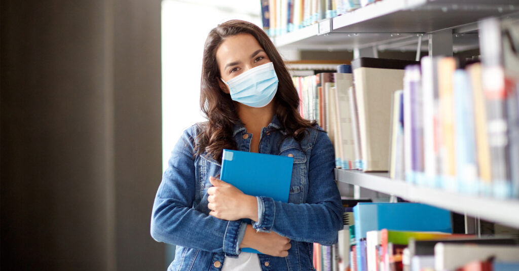 Woman in Christian school library wearing mask during coronavirus pandemic.
