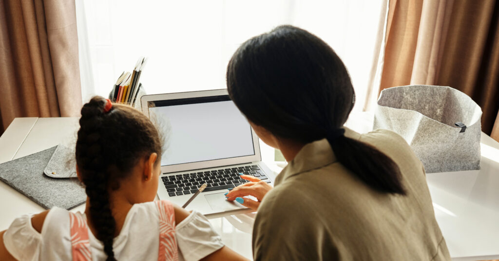 Mother helps daughter with online learning.