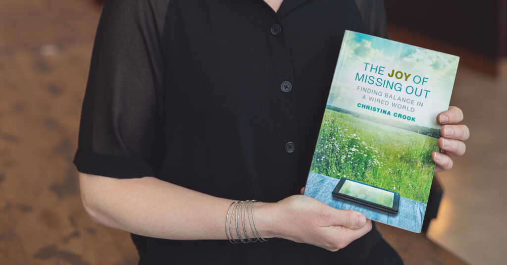 Christina Crook holding a copy of her book "The Joy of Missing Out" about digital wellness.