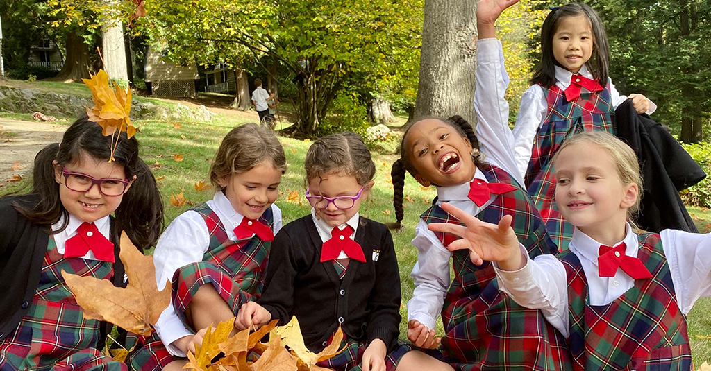 The King's School students playing in a pile of leaves.